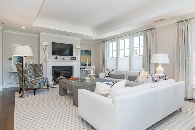 living room with crown molding, light hardwood / wood-style flooring, and a raised ceiling