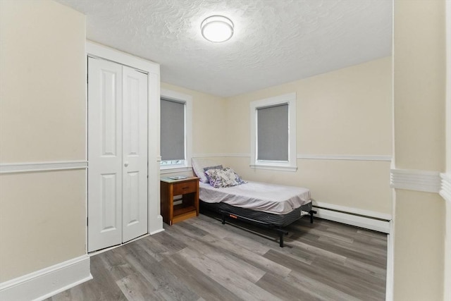357 Granite St, Quincy, MA 02169 - bedroom with baseboard heating, wood finished floors, a closet, and a textured ceiling