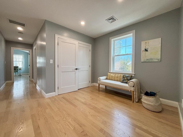 living area with light wood-style floors, visible vents, and baseboards