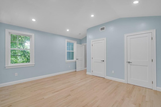 unfurnished room featuring lofted ceiling, light wood-style floors, visible vents, and baseboards