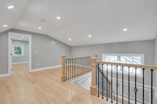 corridor featuring wood finished floors, an upstairs landing, a wealth of natural light, and vaulted ceiling