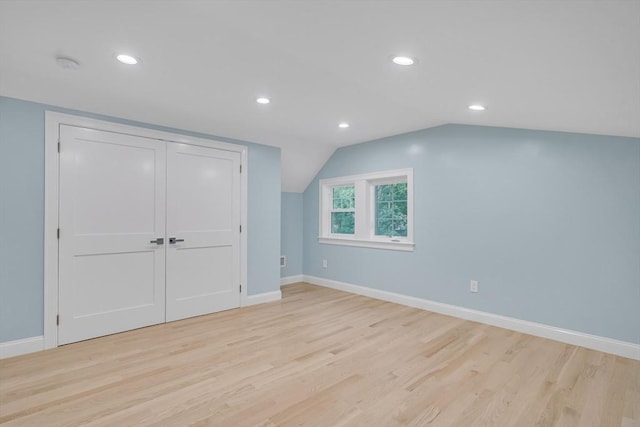 additional living space with light wood-type flooring, baseboards, and vaulted ceiling