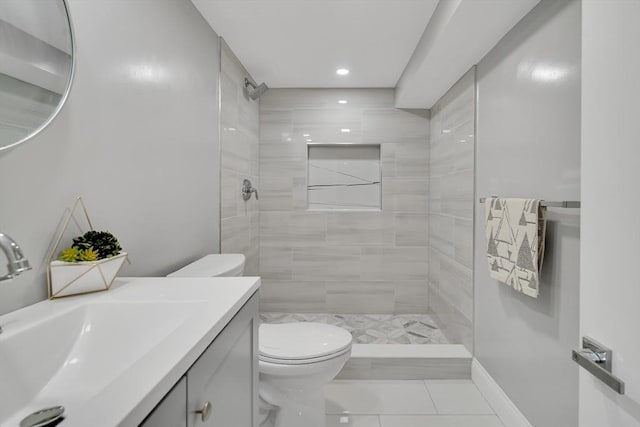 full bath featuring vanity, baseboards, tiled shower, tile patterned floors, and toilet