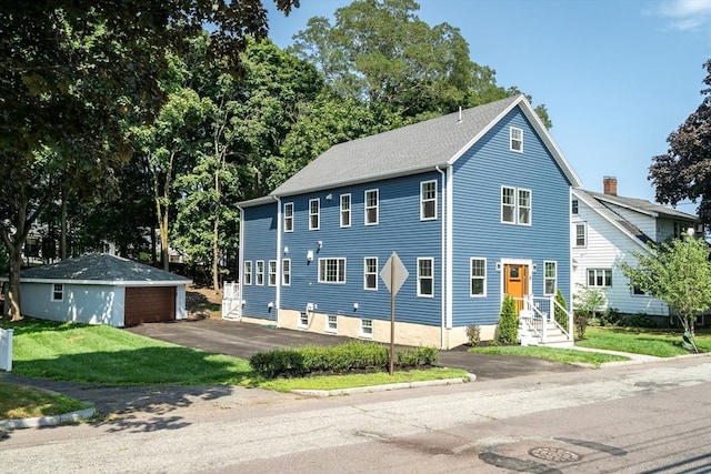 colonial inspired home with a detached garage, an outdoor structure, and a front lawn