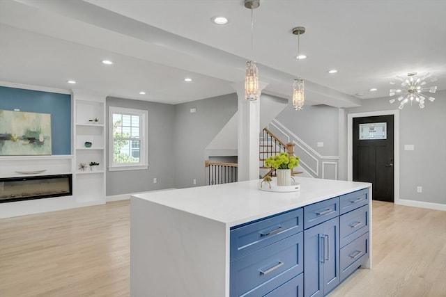 kitchen featuring a glass covered fireplace, decorative light fixtures, recessed lighting, and light wood-type flooring