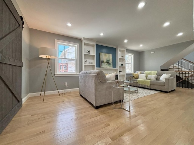 living area with stairway, baseboards, recessed lighting, light wood-style floors, and a barn door