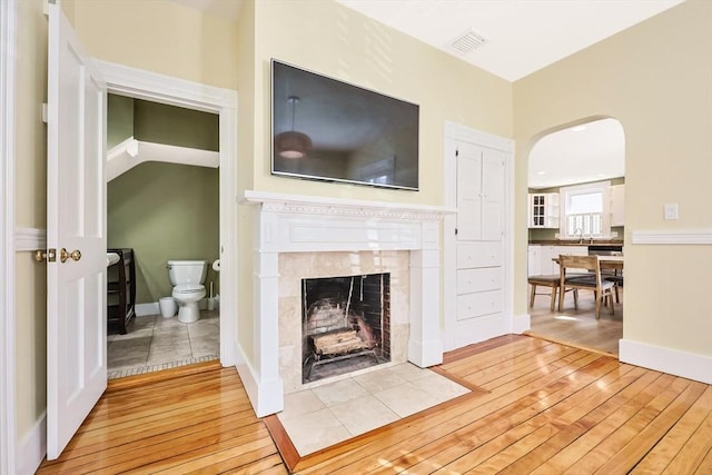 113 Taylor St Unit 1, Waltham, MA 02453 - living room with visible vents, arched walkways, hardwood / wood-style flooring, and a tile fireplace