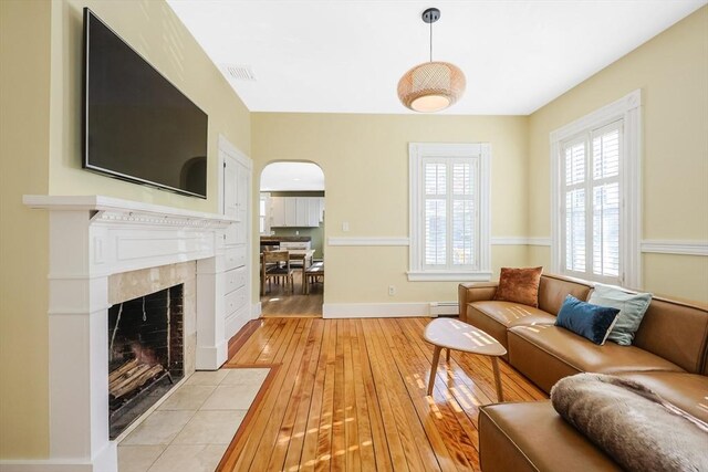 113 Taylor St Unit 1, Waltham, MA 02453 - living room with arched walkways, a baseboard radiator, a healthy amount of sunlight, and light wood-style floors