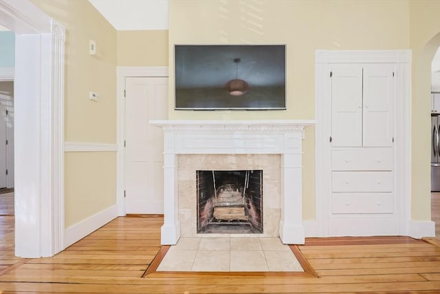 113 Taylor St Unit 1, Waltham, MA 02453 - room details with freestanding refrigerator, wood finished floors, a fireplace, baseboards, and arched walkways