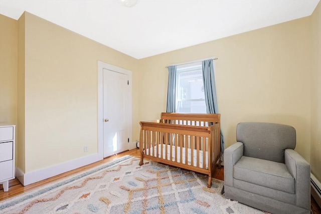 113 Taylor St Unit 1, Waltham, MA 02453 - bedroom featuring baseboards, light wood-type flooring, and a crib