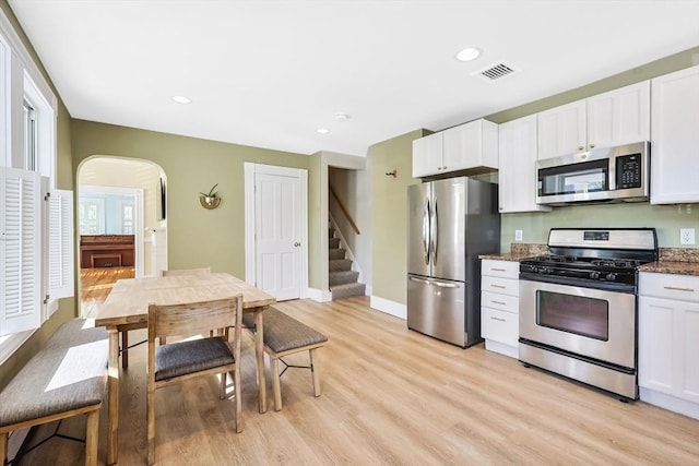 113 Taylor St Unit 1, Waltham, MA 02453 - kitchen with arched walkways, light wood finished floors, appliances with stainless steel finishes, and white cabinets