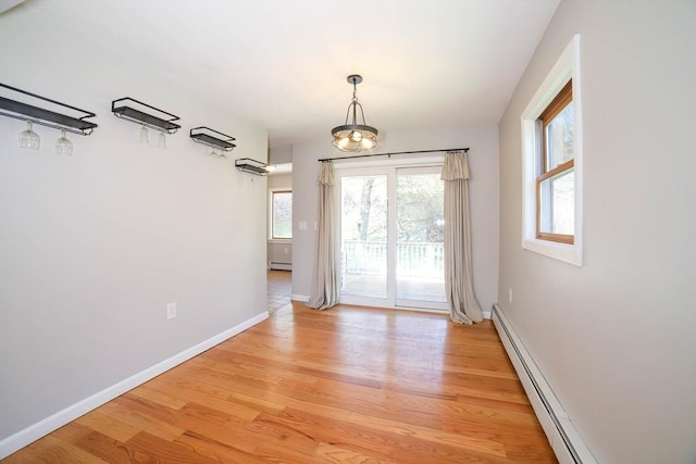 unfurnished dining area with baseboards, a baseboard heating unit, and light wood-type flooring