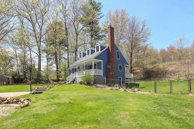 exterior space featuring fence, a yard, a chimney, and covered porch