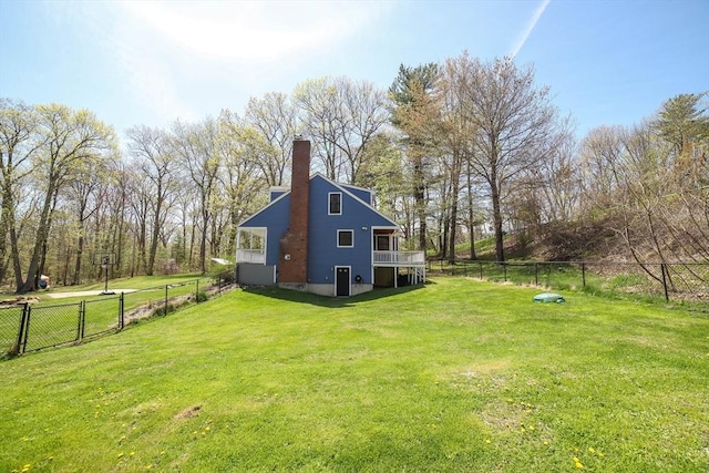 rear view of house with a fenced backyard, a chimney, and a lawn