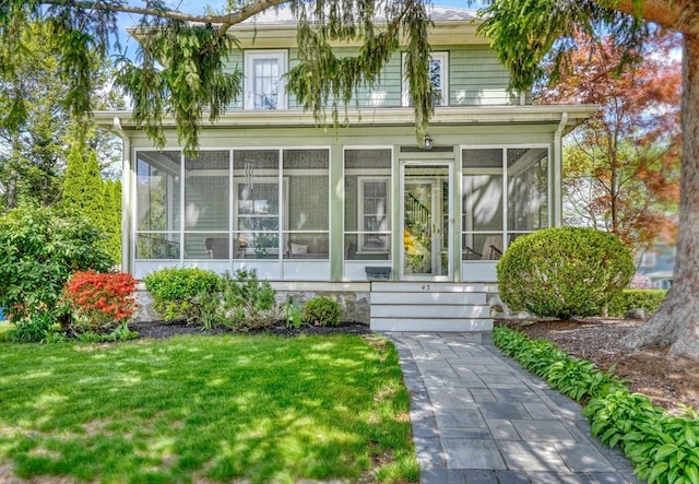 rear view of property with a sunroom and a yard
