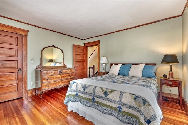 bedroom featuring hardwood / wood-style floors, ornamental molding, and baseboards
