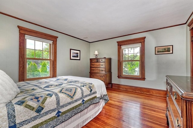 bedroom with wood finished floors, multiple windows, ornamental molding, and baseboards