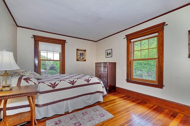 bedroom with hardwood / wood-style floors, crown molding, and baseboards