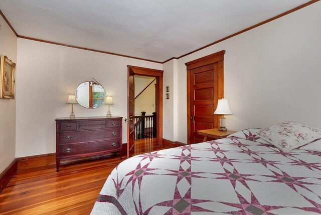 bedroom featuring ornamental molding, wood finished floors, and baseboards