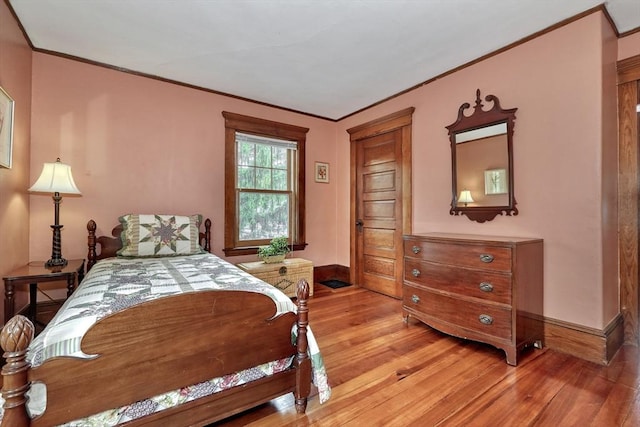 bedroom featuring ornamental molding, light wood-style floors, and baseboards
