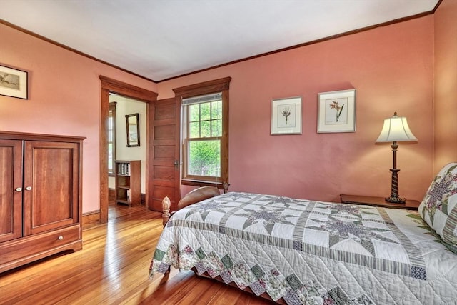 bedroom with light wood-type flooring, ornamental molding, and baseboards