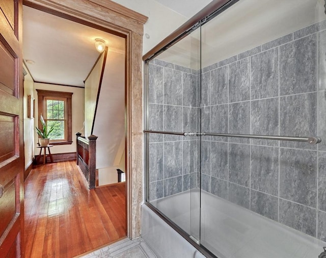 bathroom featuring hardwood / wood-style flooring and bath / shower combo with glass door