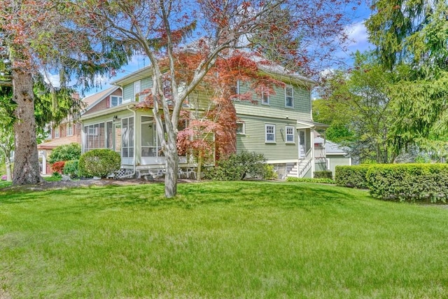 rear view of property with a lawn and a sunroom