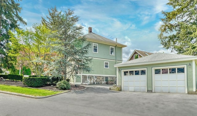 view of side of home featuring a chimney, an outbuilding, and a detached garage