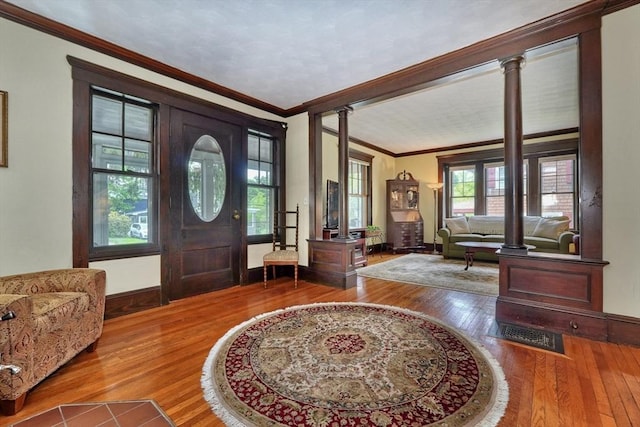 entryway with crown molding, decorative columns, wood-type flooring, and baseboards