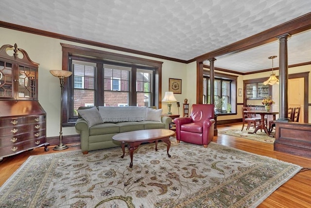 living area featuring plenty of natural light, ornate columns, baseboards, and crown molding