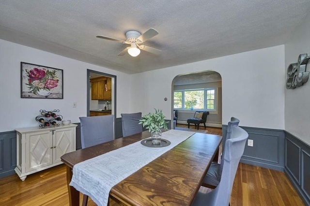 10 Locust St, Burlington, MA 01803 - dining space featuring arched walkways, a ceiling fan, a wainscoted wall, wood finished floors, and a textured ceiling