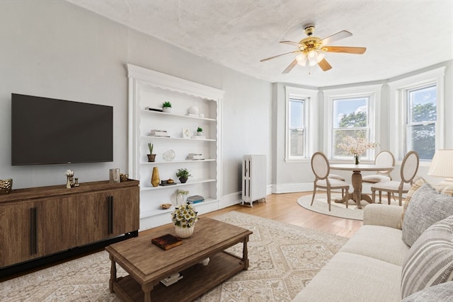 living room featuring light hardwood / wood-style floors, a textured ceiling, radiator, and ceiling fan