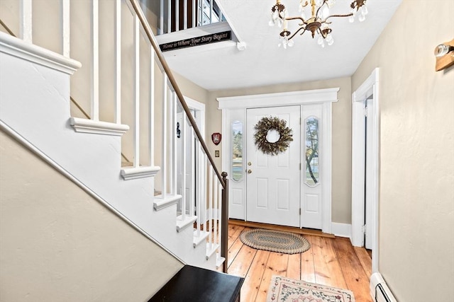 foyer entrance featuring an inviting chandelier, hardwood / wood-style flooring, and a baseboard radiator