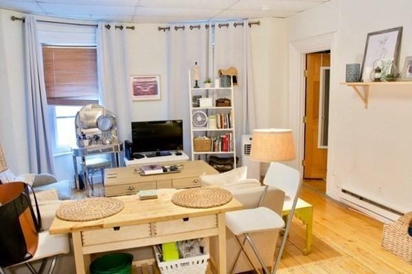 living area featuring light hardwood / wood-style flooring, a paneled ceiling, and baseboard heating