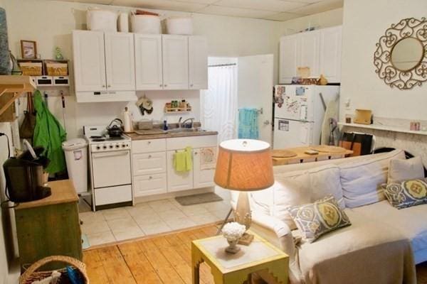 kitchen with sink, white appliances, light hardwood / wood-style flooring, a paneled ceiling, and white cabinets