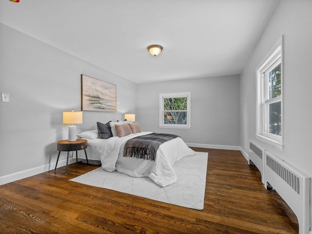 bedroom with multiple windows, radiator heating unit, and dark hardwood / wood-style floors