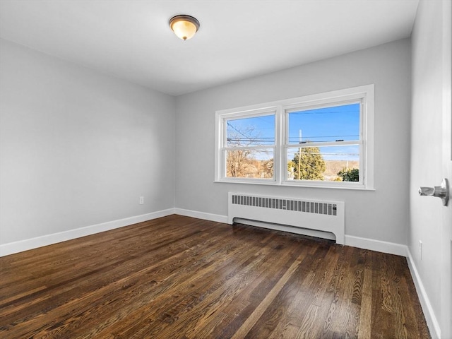 empty room featuring radiator heating unit and dark hardwood / wood-style floors