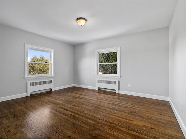 unfurnished living room featuring dark wood-type flooring, radiator heating unit, and plenty of natural light