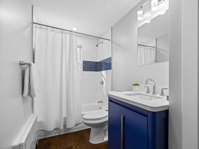 full bathroom featuring radiator, hardwood / wood-style flooring, vanity, shower / bath combination with curtain, and toilet