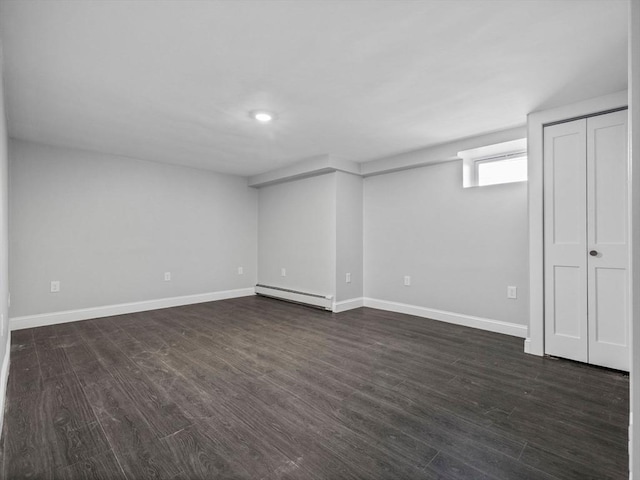 basement with a baseboard radiator and dark hardwood / wood-style floors