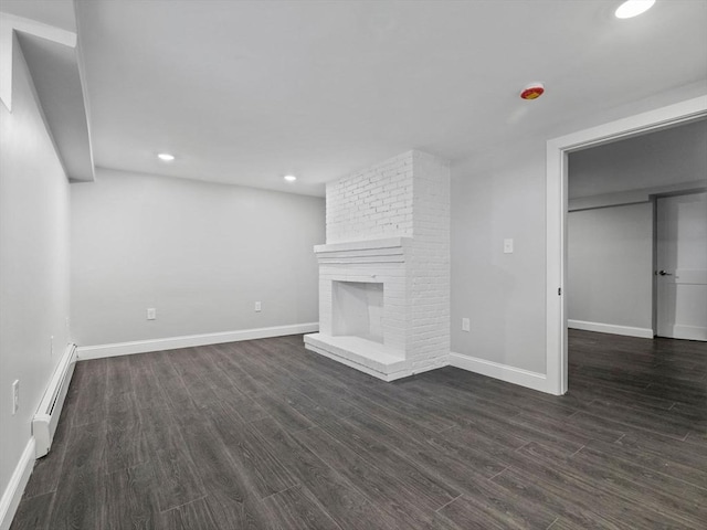 unfurnished living room with a baseboard heating unit, dark wood-type flooring, and a fireplace