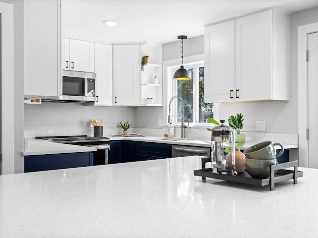 kitchen with sink, pendant lighting, stainless steel appliances, light stone countertops, and white cabinets