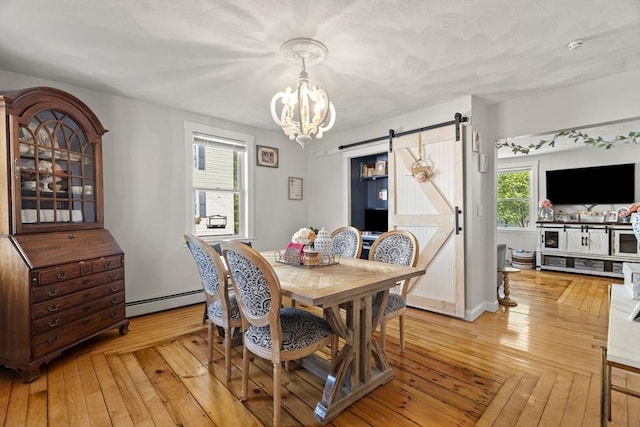 dining area with a notable chandelier, a barn door, baseboard heating, and light wood-style flooring