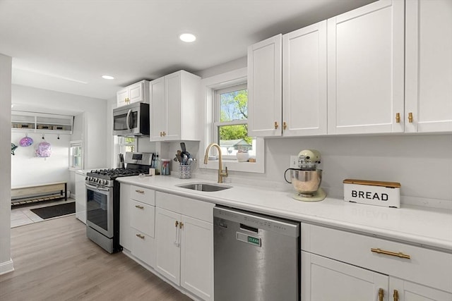 kitchen with light countertops, stainless steel appliances, white cabinetry, and a sink