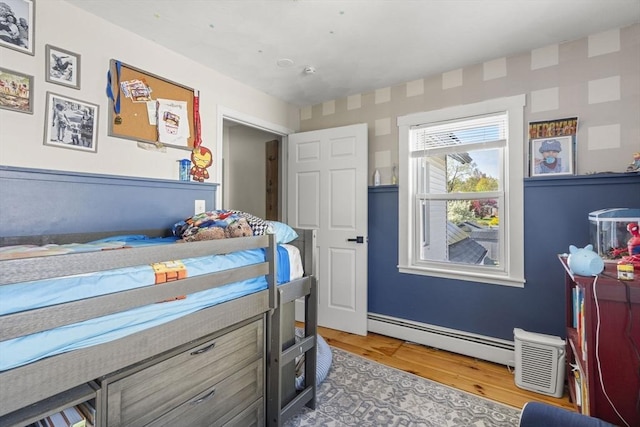 bedroom featuring baseboards, baseboard heating, and light wood finished floors