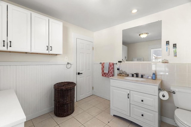 bathroom featuring vanity, toilet, tile patterned flooring, and a wainscoted wall