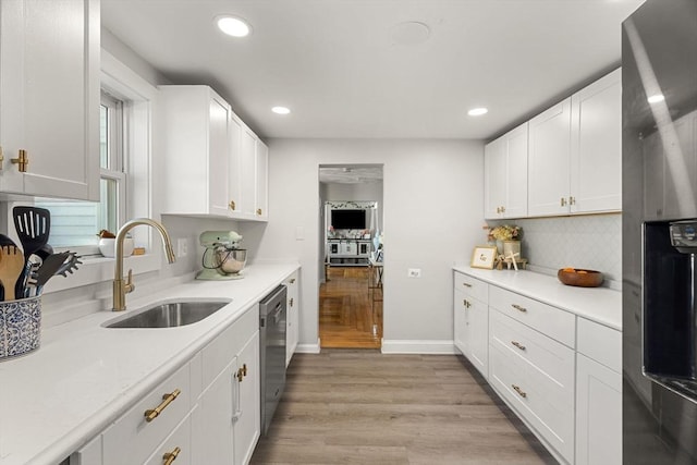 kitchen featuring light countertops, appliances with stainless steel finishes, a sink, and light wood finished floors