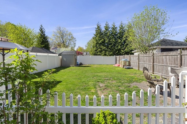 view of yard with an outdoor structure, a fenced backyard, and a storage unit