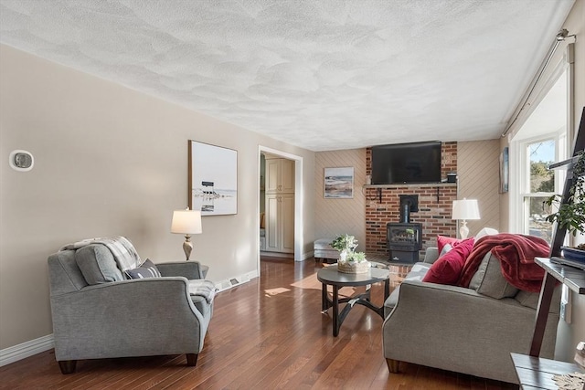 living room with a wood stove, a textured ceiling, and dark hardwood / wood-style floors