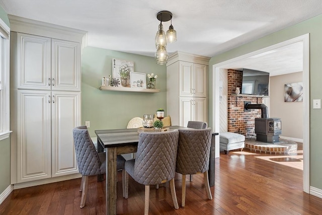 dining room with dark wood-type flooring and a wood stove